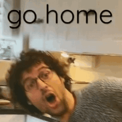 A Man With Glasses Is Making A Funny Face In A Kitchen With The Words `` Go Home '' Behind Him . GIF
