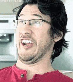 A Man With Glasses Is Making A Funny Face With His Mouth Open . GIF