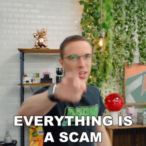 A Man With Glasses Is Pointing At The Camera With The Words Everything Is A Scam Behind Him GIF