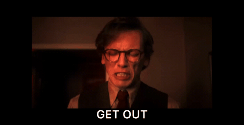 A Man With Glasses Is Screaming In A Dark Room With The Words Get Out Above Him GIF
