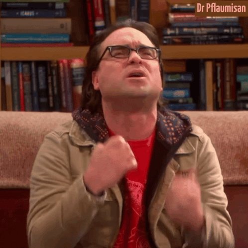 A Man With Glasses Is Sitting On A Couch In Front Of A Bookshelf With Dr Pflaumisan Written On The Top GIF