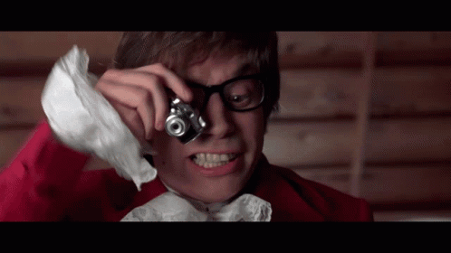 A Man With Glasses Is Taking A Picture With A Small Camera GIF