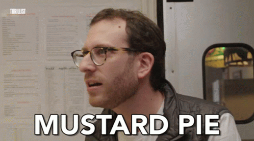 A Man With Glasses Says Mustard Pie In Front Of A Menu Board GIF