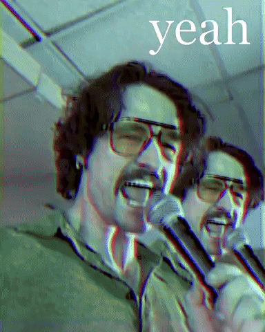 A Man With Glasses Singing Into A Microphone With The Word Yeah Behind Him GIF