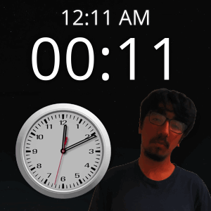 A Man With Glasses Stands Next To A Clock That Says 12:11 Am GIF