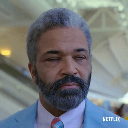A Man With Gray Hair And A Beard Is Wearing A Blue Suit And Tie With Netflix Written Below Him GIF