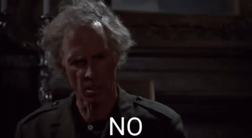 A Man With Gray Hair And A Black Jacket Is Standing In A Dark Room And Saying No . GIF