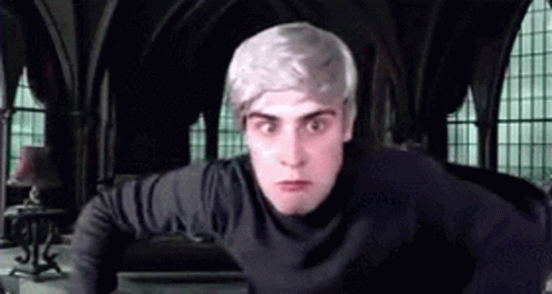 A Man With Gray Hair And A Black Shirt Is Standing In A Room With Arched Windows . GIF