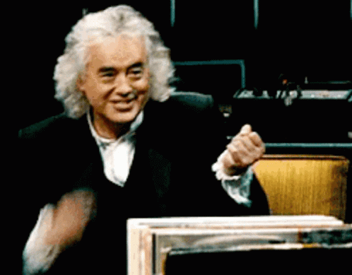 A Man With Gray Hair And A Black Suit Is Smiling And Clapping His Hands GIF