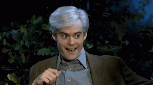 A Man With Gray Hair Is Smiling And Pointing At Something GIF