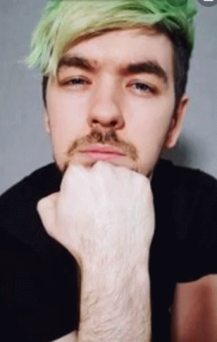 A Man With Green Hair And A Beard Holds His Hand To His Chin GIF