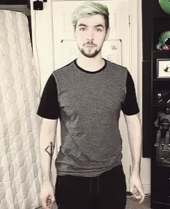 A Man With Green Hair And A Beard Is Standing In Front Of A Mattress . GIF