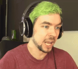 A Man With Green Hair And Headphones On Is Making A Funny Face . GIF