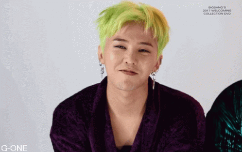 A Man With Green Hair Is Wearing A Purple Jacket And Earrings GIF