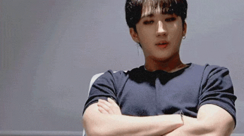 A Man With His Arms Crossed Is Wearing A Black Shirt And Earrings GIF