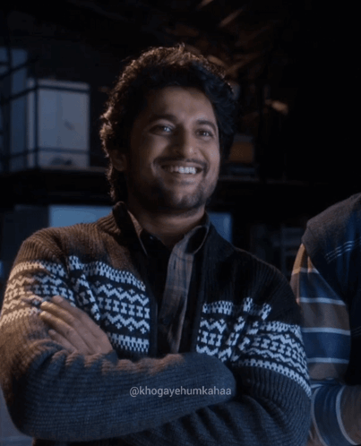 A Man With His Arms Crossed Is Wearing A Sweater With A Pattern On It GIF