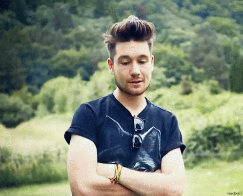 A Man With His Arms Crossed Wearing A Black Shirt With A Cat On It . GIF