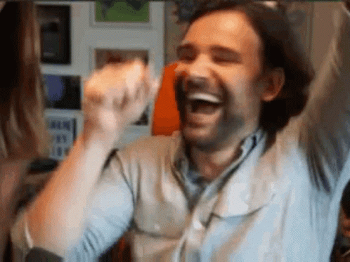 A Man With His Arms In The Air Is Laughing And Celebrating . GIF