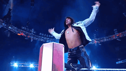 A Man With His Arms In The Air Stands On A Podium GIF