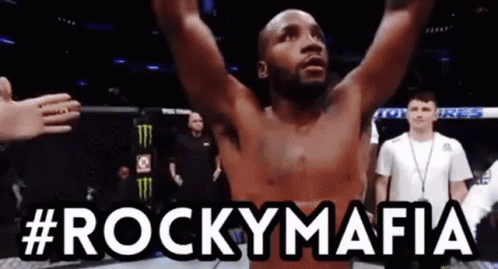 A Man With His Arms In The Air With #Rockymafia Written Above Him GIF
