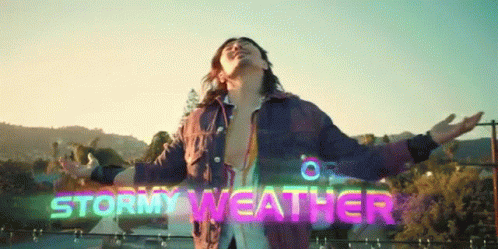 A Man With His Arms Outstretched In Front Of A Sign That Says " Stormy Weather " GIF