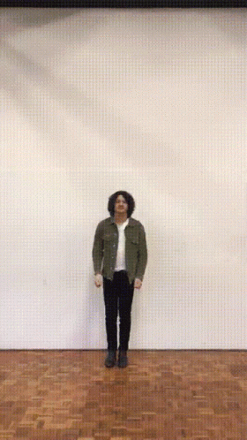 A Man With His Arms Outstretched Is Standing On A Wood Floor GIF