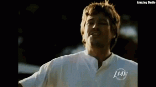 Man With Arms Outstretched Wearing White Shirt With LMN GIF