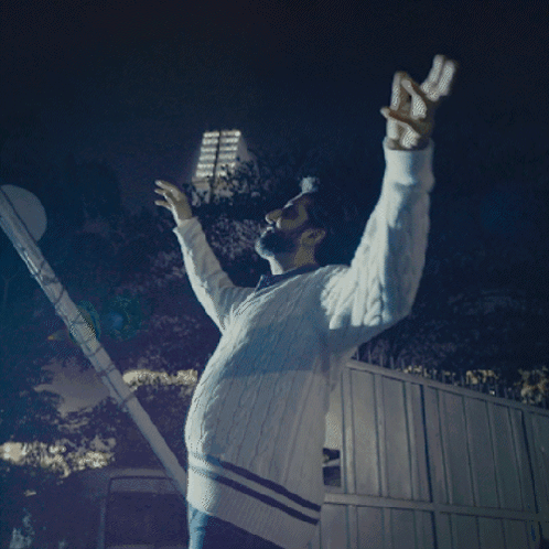 A Man With His Arms Outstretched Is Wearing A White Sweater With Blue Stripes GIF