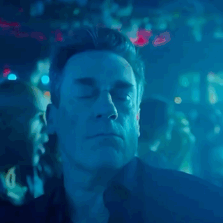 a man with his eyes closed in a dark room with blue lights behind him