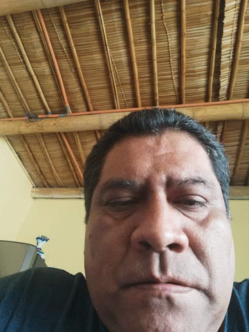 A Man With His Eyes Closed In Front Of A Straw Roof GIF