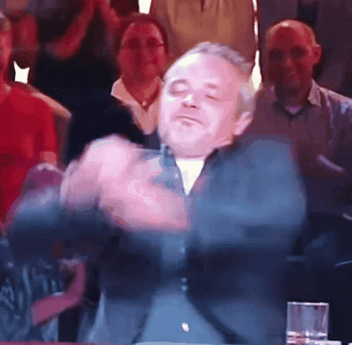 A Man With His Eyes Closed Is Dancing In Front Of A Crowd GIF
