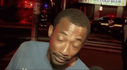 A Man With His Eyes Closed Is Standing In Front Of A Sign That Says Ice Cold Beer GIF