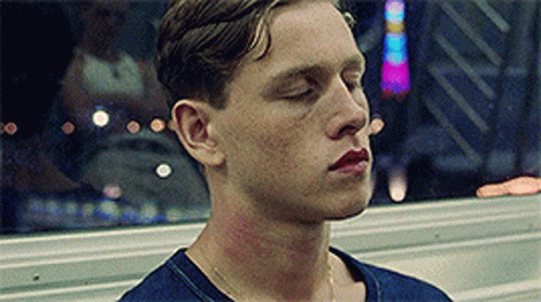 A Man With His Eyes Closed Is Wearing A Blue Shirt . GIF