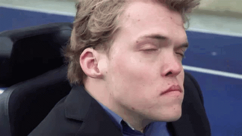 A Man With His Eyes Closed Is Wearing A Suit And A Blue Shirt GIF