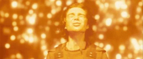 A Man With His Eyes Closed Stands In Front Of A Blurred Background Of Lights GIF