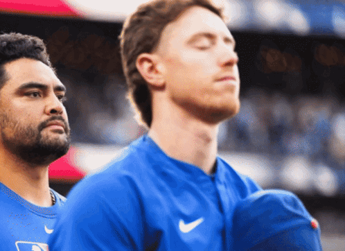 A Man With His Eyes Closed Stands Next To Another Man GIF