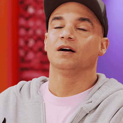 A Man With His Eyes Closed Wearing A Hat And A Gray Hoodie GIF