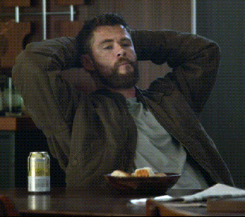 A Man With His Hands Behind His Head Sits At A Table With A Can Of Beer On It GIF