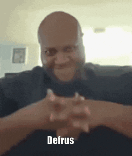 A Man With His Hands Folded And The Word Defrus On The Bottom Right GIF