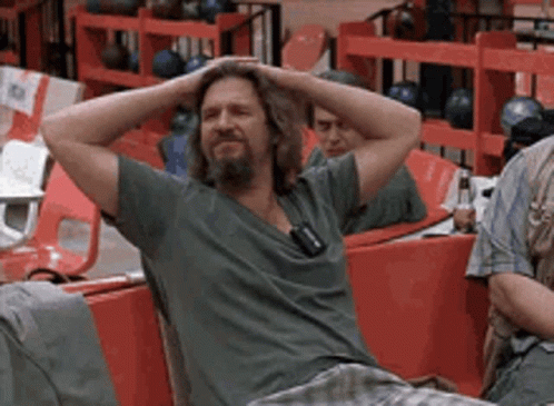 A Man With His Hands On His Head Is Sitting In A Bowling Alley GIF