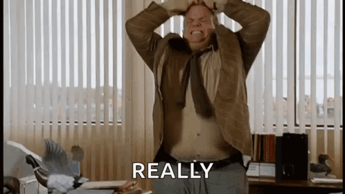 A Man With His Hands On His Head Is Standing In Front Of A Window With The Word Really Written On It . GIF