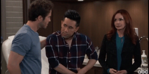 A Man With His Hands On His Stomach Is Talking To A Woman And A Man In A Blue Shirt GIF
