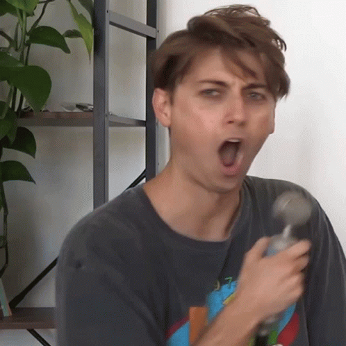 A Man With His Mouth Open Is Holding A Hammer In His Hand GIF