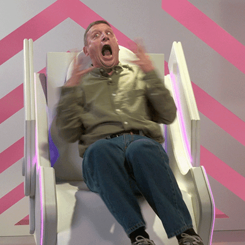 A Man With His Mouth Open Is Sitting In A Chair GIF