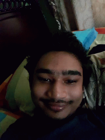 A Man With His Tongue Out Is Laying On A Bed GIF