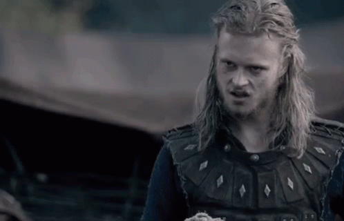 a man with long blonde hair and a beard is wearing a black vest and a black shirt .