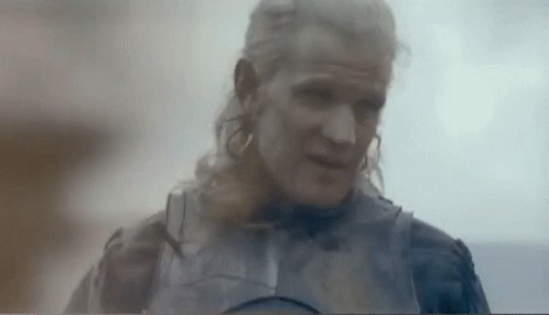 a man with long blonde hair and a beard is wearing a knight 's armor .