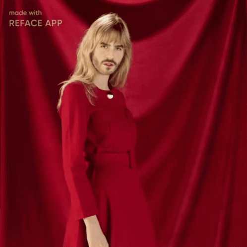 A Man With Long Blonde Hair And A Beard Is Wearing A Red Dress GIF