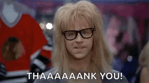 A Man With Long Blonde Hair And Glasses Is Standing In A Crowd . GIF