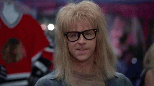 A Man With Long Blonde Hair And Glasses Is Standing In Front Of A Hockey Jersey . GIF